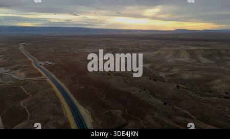 Aus der Vogelperspektive einer langen, geraden Straße durchquert die trockene Landschaft unter einem weiten Himmel, der von sanften Morgentönen getönt ist, Fruita, Colorado, United Stat Stockfoto