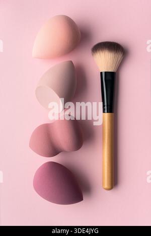 Minimales Make-up auf rosa Hintergrund mit weichen Schwämmen und Pinsel. Sauberes, feminines Beauty-Konzept mit Schwerpunkt auf sanfter Hautpflege, ruhiger Routine und Mode Stockfoto