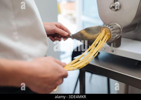 Nahaufnahme von Händen, die Teig durch den industriellen Teigschneider führen Stockfoto