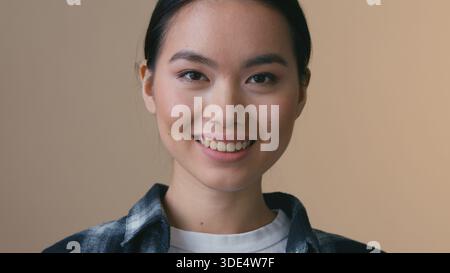 Asiatische koreanische Frau entfernt medizinische Maske abnehmend innen lächelndes weibliches japanisches Mädchen zahniges Lächeln Gefühl Erleichterung Ende der COVID19 Pandemie Erholung Stockfoto