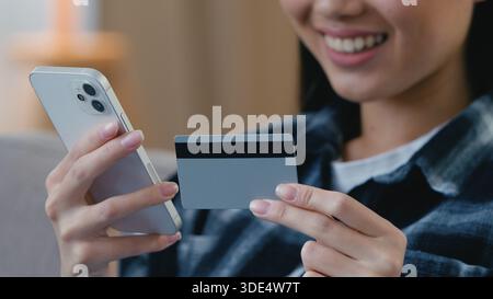 Glückliche freudige nicht erkennbare asiatische Frau, die online Handy bezahlt, Bank Kreditkarte macht Internet-Zahlung koreanische japanische weibliche Hände Stockfoto