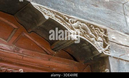 Detailaufnahme eines geschnitzten architektonischen Bauteils aus Holz mit traditionellen Motiven, die komplexe Handwerkskunst und kulturelles Erbe hervorheben. Stockfoto