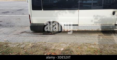 Nahaufnahme des hinteren Abschnitts des heruntergekommenen weißen Transporters mit erheblichen Rostschäden entlang der unteren Seite und des Radkastens, sichtbarer Reifenpanne, Par Stockfoto