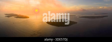 Ein beschaulicher und farbenfroher Sonnenaufgang bildet die Fam Islands in Raja Ampat, Indonesien. Dieses tropische Gebiet bietet eine spektakuläre Meeresvielfalt. Stockfoto