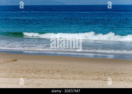 Landschaft mit Wellenschaum am Wasserrand am sandigen Ufer der Plettenberg Bay, aufgenommen im hellen Licht des späten Frühlings am Wedge Beach, Plettenberg, Western Cape, S Stockfoto