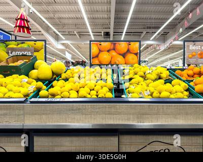 Gestapelte Tabletts mit gelben Zitrusfrüchten einschließlich Zitronen und Melonen, die in einem tesco Supermarkt Obst & Gemüse Sektion in großbritannien unter Leuchtstofflampen ausgestellt werden Stockfoto