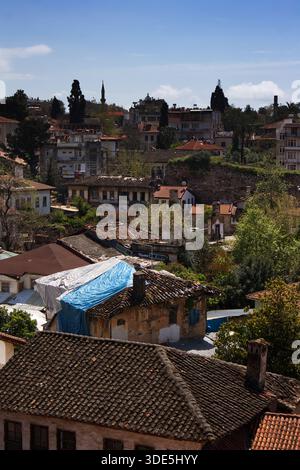 Blick auf die roten Ziegeldächer in Kaleici, Antalya, Türkei. Historische osmanische Häuser und Palmen unter blauem Himmel in der Altstadt. Stockfoto