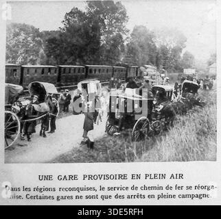 Dieses Archivfoto von Le Miroir aus dem Jahr 1914 veranschaulicht die logistischen Herausforderungen des Ersten Weltkriegs in den zurückeroberten französischen Gebieten. Als sich die Frontlinien verlagerten, kämpfte der Eisenbahnverkehr um die Reorganisation, was zur Schaffung von provisorischen Bahnhöfen auf offenen Feldern führte. Das Bild zeigt einen Zug, der auf dem Land hält, wo Pferdekutschen und Fahrgäste in einem provisorischen Transitknotenpunkt aufeinander treffen. Er hebt die Widerstandsfähigkeit der Infrastruktur und die unmittelbaren Anstrengungen zur Wiederherstellung lebenswichtiger Verkehrsverbindungen im Chaos des Konflikts hervor. Stockfoto