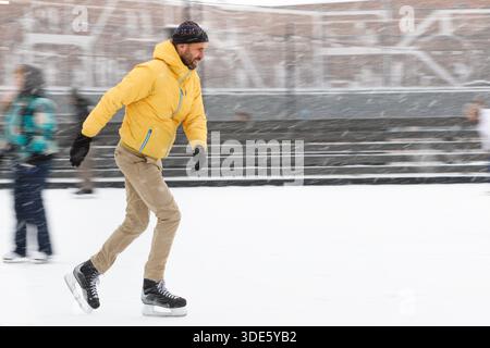 Bärtiger Mann mittleren Alters auf der Eisbahn, draußen an schneebedeckten Wintertagen Stockfoto
