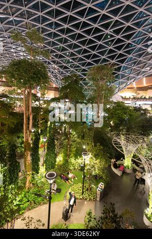 Die Menschen entspannen sich im Hamad International Airport in Doha, Katar, einem üppigen Innengarten, der einen ruhigen Zufluchtsort bietet. Stockfoto