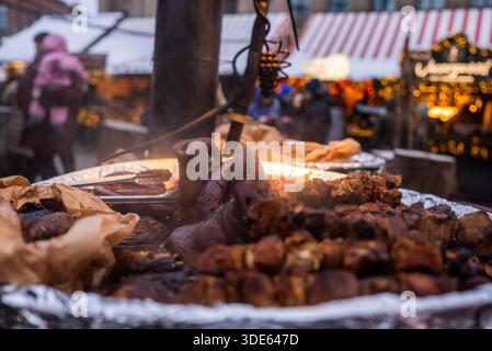 Rustikales Fleisch auf dem dampfenden Grill auf dem Rigaer Weihnachtsmarkt in Lettland Stockfoto