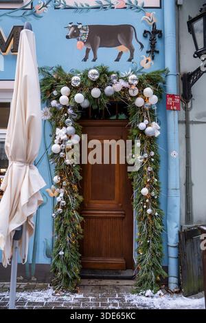 Festliche Holztür und Kuhgemälde an Pastellfassade in Riga, Lettland Stockfoto