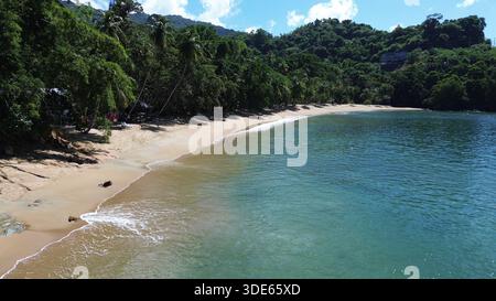 Blick aus der Vogelperspektive auf die Englishman’s Bay in Tobago mit einem abgeschiedenen sicheligen Strand, türkisfarbenem karibischem Wasser und üppigem tropischem Regenwald. Stockfoto