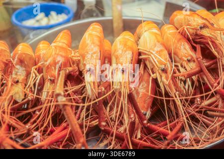 Frisch gedämpfte Garnelen in einem Metalltablett auf einem thailändischen Lebensmittelmarkt. Hauptzutat für Tom Yum Suppe und authentische asiatische Meeresfrüchte Küche. Stockfoto