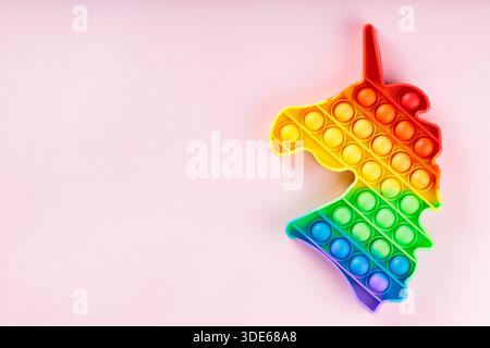 Rainbow Unicorn Pop it zappeln Spielzeug auf rosa Hintergrund mit Copy Space Sensory Anti Stress Konzept Stockfoto