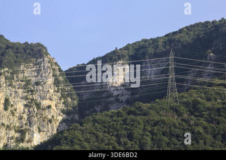 Stromleitungen, die bei Sonnenuntergang über eine Klippe eines Berges führen Stockfoto
