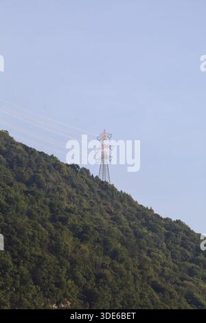 Stromleitungen, die bei Sonnenuntergang über eine Klippe eines Berges führen Stockfoto