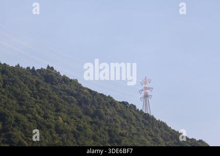 Stromleitungen, die bei Sonnenuntergang über eine Klippe eines Berges führen Stockfoto