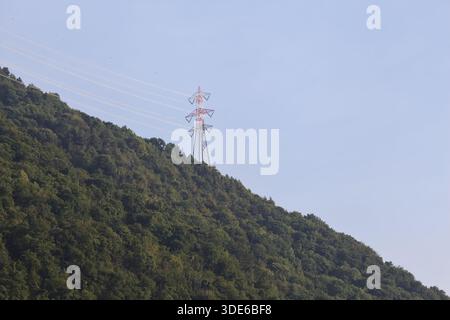 Stromleitungen, die bei Sonnenuntergang über eine Klippe eines Berges führen Stockfoto