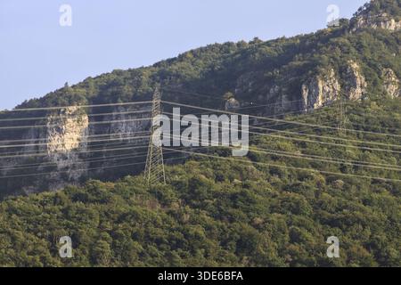 Stromleitungen, die bei Sonnenuntergang über eine Klippe eines Berges führen Stockfoto