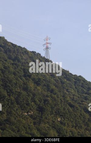 Stromleitungen, die bei Sonnenuntergang über eine Klippe eines Berges führen Stockfoto