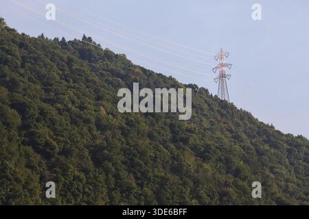 Stromleitungen, die bei Sonnenuntergang über eine Klippe eines Berges führen Stockfoto