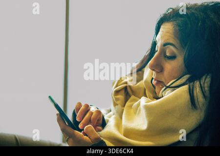 Eine schöne Frau, die auf ihr Handy blickt. Die Frau ist 39 Jahre alt und hat lange schwarze Haare Stockfoto
