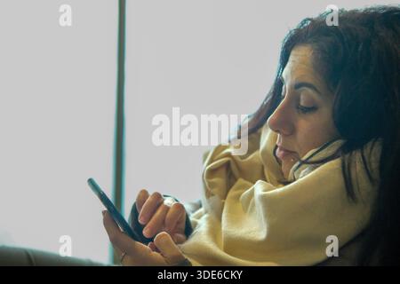 Eine schöne Frau, die auf ihr Handy blickt. Die Frau ist 39 Jahre alt und hat lange schwarze Haare Stockfoto