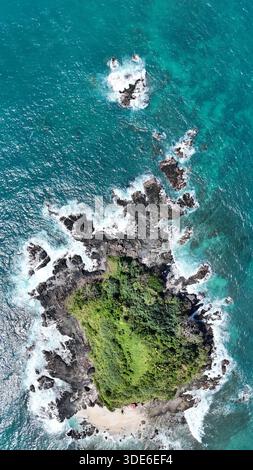 Eine verlorene Insel auf den philippinen ohne Menschen und ohne Leben. Felsige Klippen und große Wellen, die an den Rand stoßen. Die Mitte ist grün, voller Gras Stockfoto