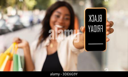 Frau zeigt Handy mit schwarzem freitagstext auf dem Bildschirm Stockfoto