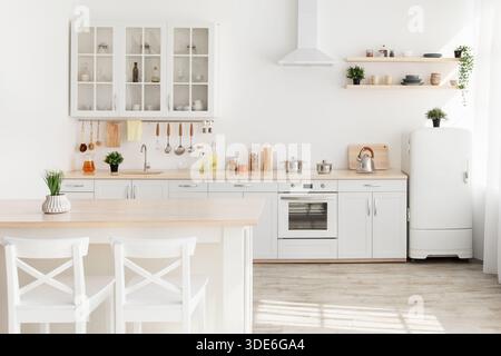 Esszimmer und Kücheneinrichtung. Pflanzen auf Holztisch mit weißen Stühlen, Küchenutensilien und modernen Möbeln Stockfoto