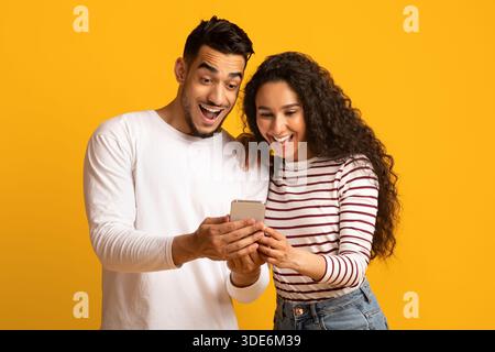 Coole App Aufgeregt arabischen Paar Blick auf Smartphone-Bildschirm in den Händen Stockfoto