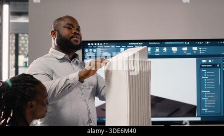 Stadtentwicklung Diversität Team diskutiert Immobilieninvestitionen neue Strategie für die Projektgenehmigung in einem hellen Büroumfeld, analysiert Blaupausen und 3D-Modelle auf Architektursoftware. Stockfoto