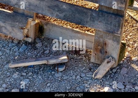 Verwitterte Holzpalette, die mit Holzstücken auf einem steinigen Boden zerbrochen ist und Verfall zeigt Stockfoto