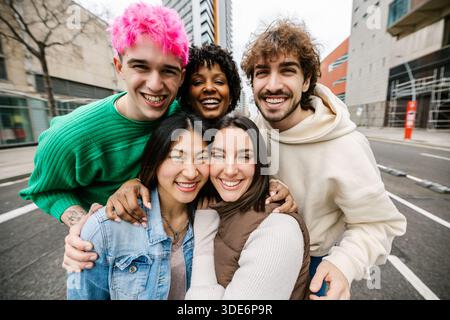 Nahaufnahme verschiedener junger Freunde, die sich umarmen und im Freien lächeln Stockfoto