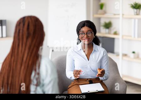 Psychotherapieberatung. Ein Berater, der mit einer schwarzen Frau beim Treffen im Büro spricht und einem jungen Klienten Ratschläge gibt Stockfoto