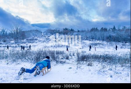 Schneebedeckte Winterlandschaft im Volkspark Prenzlauer Berg, Berlin, zeigt eine der markanten Hügel des Parks. Kinder Schlitten fahren, Schlitten fahren. Stockfoto