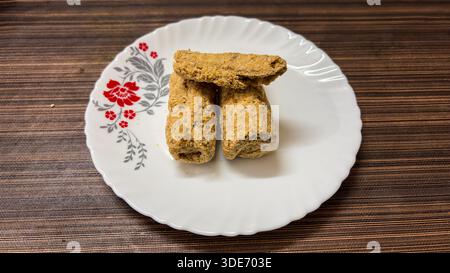 Traditionelle indische Süßigkeiten Sesambrüchig oder Tilkut serviert auf weißer Keramikplatte mit Blick von oben Stockfoto