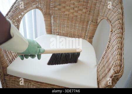 Einen Stuhl mit einer Bürste in einem hellen Raum reinigen Stockfoto