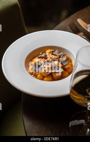 Nahaufnahme cremiger Gnocchi mit rasierten schwarzen Trüffeln, die ein elegantes italienisches Gourmet-Gericht präsentieren. Stockfoto