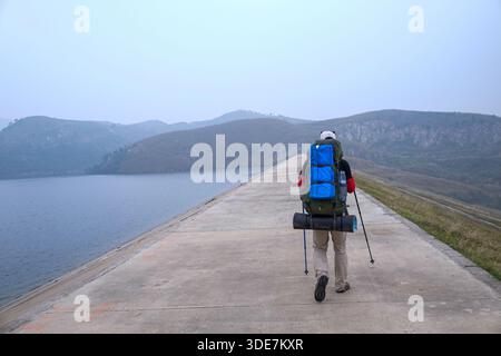 WUHAN, PROVINZ HUBEI, CHINA - 31. OKTOBER 2014: Rückansicht von Outdoor-Enthusiasten mit schweren Rucksäcken, die über einen Betonstaudamm im L wandern Stockfoto
