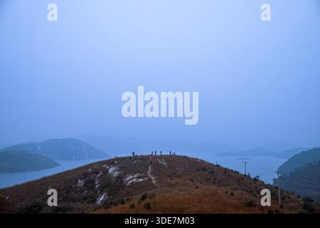 WUHAN, CHINA - 31. OKTOBER 2014: Panoramablick auf den Longwangjian Bergkamm, bedeckt mit trockenem Herbstgras. Winzige Figuren von Wanderern sind zu sehen Stockfoto