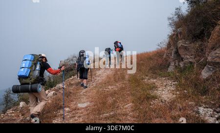 WUHAN, CHINA - 31. OKTOBER 2014: Rückansicht von Wanderern mit großen Rucksäcken auf unterschiedlichem Gelände. Die Bilder zeigen Trekking auf felsigen Schotterwegen, Stockfoto