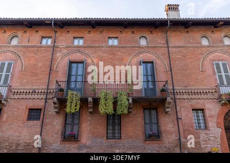 Traditionelle Backsteinfassade, die alte Architektur mit Balkonen und grünem Efeu zeigt Stockfoto