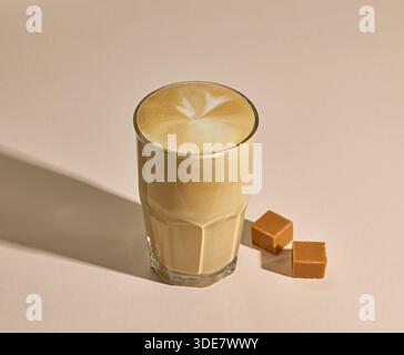 Glas Karamell Latte Kaffee auf beigefarbenem Hintergrund Stockfoto