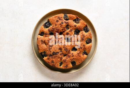 Herbstlicher hausgemachter Pflaumenkuchen auf Teller auf hellem Hintergrund. Draufsicht, flach. Stockfoto