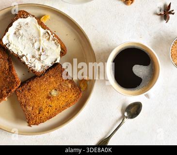 Geschnittenes Kürbisbrot mit Butter auf Teller auf hellem Steinhintergrund. Draufsicht, flach Stockfoto