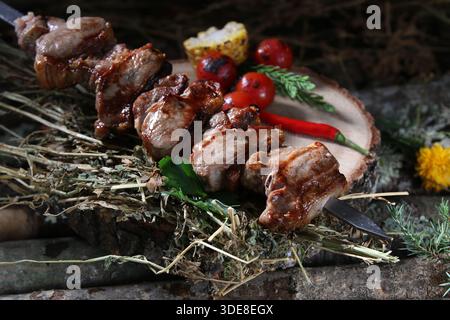 Eine Nahaufnahme eines köstlichen, rustikalen Lammschaschlik (Kebab) auf Spießen, mit Stücken gegrilltem Lammfleisch, gerösteten Kirschtomaten und Mais. Es ist ser Stockfoto