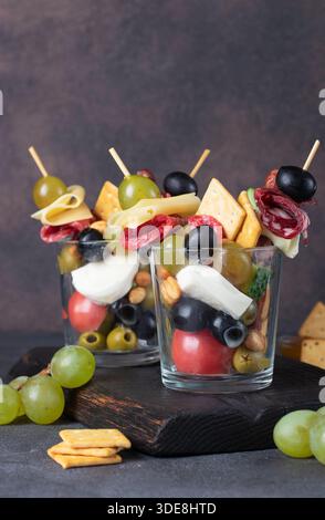 Jarcuterie in zwei Gläsern umfasst verschiedene Arten von Würsten, Gurken, Käse, Nüssen, Gemüse und Obst. Moderne Version eines festlichen Snacks Stockfoto