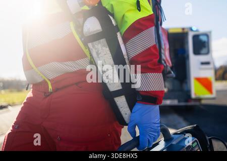 Ärztlicher Notdienst. Nahaufnahme der Sanitäter-Hand in blauen Operationshandschuhen beim Laufen mit Defibrillatormonitor und anderer Ausrüstung gegen AMB Stockfoto